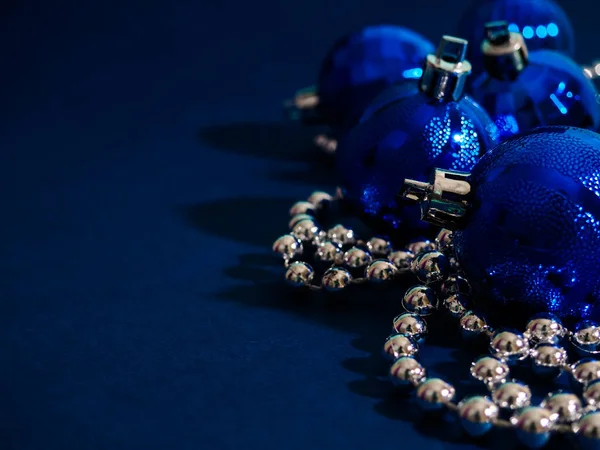 Niebieska świąteczna kula ze srebrnymi koralikami. Efekt Bokeh na ciemnym tle. Copyspace na powitanie lub życzenia, baner — Zdjęcie stockowe