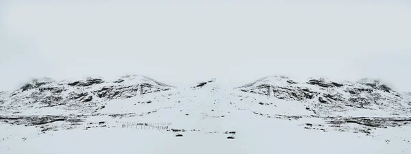 Panoramisch uitzicht op plateau in hoge besneeuwde bergen bedekt sneeuw op zonnige lentedag. de snelweg, de sneeuwberg en de blauwe lucht met witte wolken onder het winterzonlicht. bergen van Scandinavië — Stockfoto
