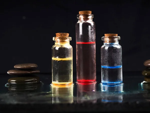 Flacon de verre liquide coloré à fond noir pour la recherche médicale. Dans un laboratoire de chimie Flacon de verre avec bouchon de liège en noir. Plusieurs petits flacons de verre avec bouchon de liège — Photo