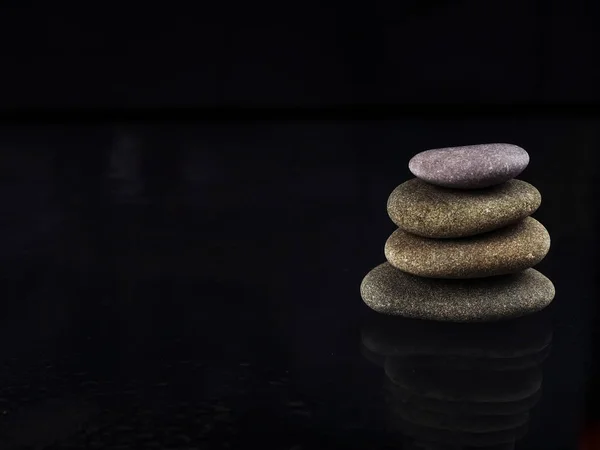 Balneario Stones. piedras zen brillantes negras con gotas de agua sobre fondo negro. Piedras Zen se amontonan en gotas de lluvia, concepto de calma, paz — Foto de Stock