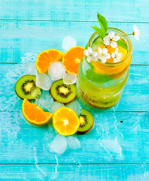Detoxikační vodní koktejl. Zdravotní nápoj s ledem kiwi a oranžové na modrém dřevěném pozadí, hubnutí — Stock fotografie