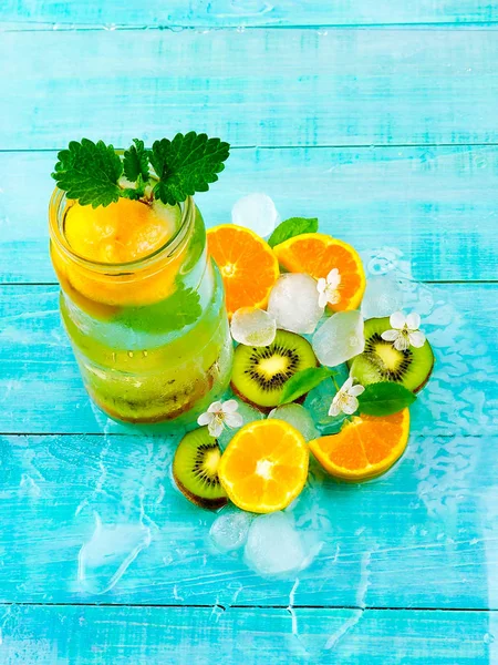 Detox water cocktail. health drink with ice kiwi and orange on blue wooden background, slimming
