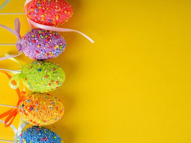 Paskalya tatili geçmişi. Parlak sarı arka planda renkli paskalya yumurtaları..