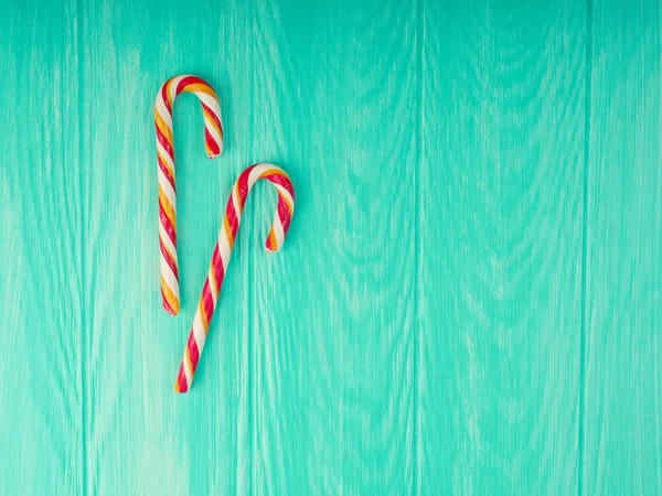 Caña de caramelo de Navidad. dos caña de caramelo de Navidad con marco en fondo de madera azul, espacio para el texto. Composición navideña, tarjeta postal —  Fotos de Stock