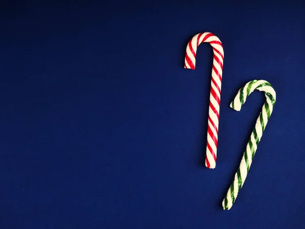 Christmas candy cane. On classic blue background. Flat lay. Christmas composition. A fan of caramel striped cane candies on a dark blue background. Minimalist New Year concept for your mockup. — Stock Photo, Image