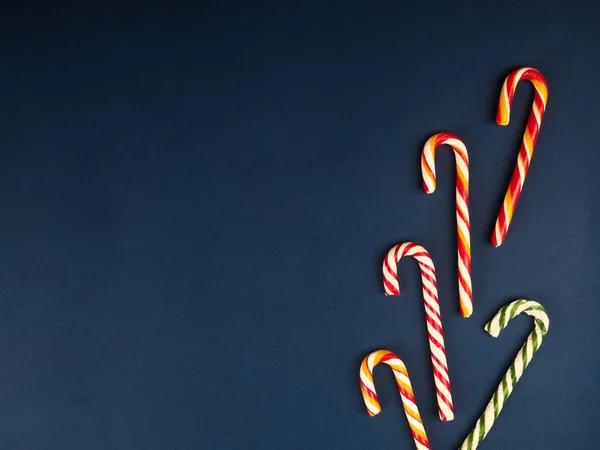Christmas candy cane. On classic blue background. Flat lay. Christmas composition. A fan of caramel striped cane candies on a dark blue background. Minimalist New Year concept for your mockup. — Stock Photo, Image