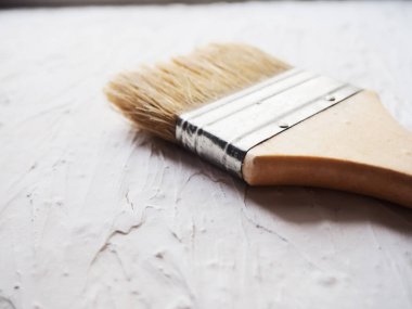 Boya işi için bir araç. Spatula ve fırça. Tamir edilecek eşyalar. Tahtaya macun sürmek için fırça ve spatula kullanan bir müteahhit. Reklam için boş yer, metin. Otantik fotoğraf, macunu onardıktan sonra gerçek fırça, gerçek tamir görüntüsü.
