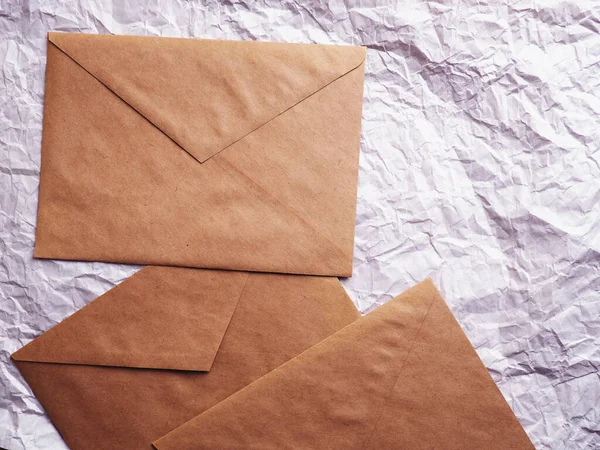 Envelope of Kraft paper lies on crumpled paper. Note from a paper on a cord of an envelope from kraft paper.