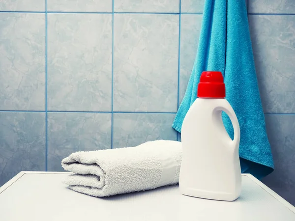 Bottle of detergent and clean towels on washing machine indoors, space for text. Laundry day.