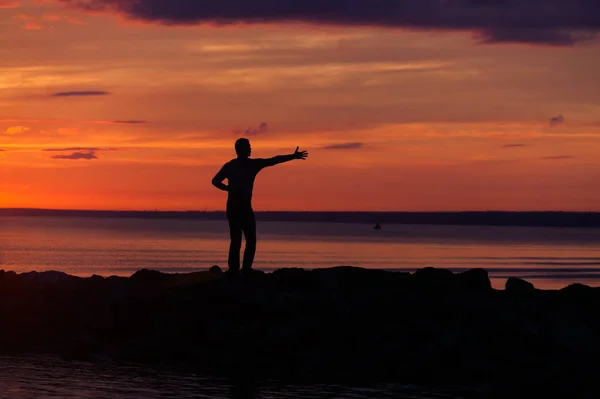 Silhuetas de mulher e homem em um fundo de pôr do sol colorido de um dia nublado na praia — Fotografia de Stock