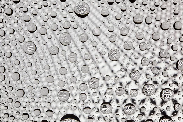Abstrakta linjer genom droppar vatten på ett glas — Stockfoto