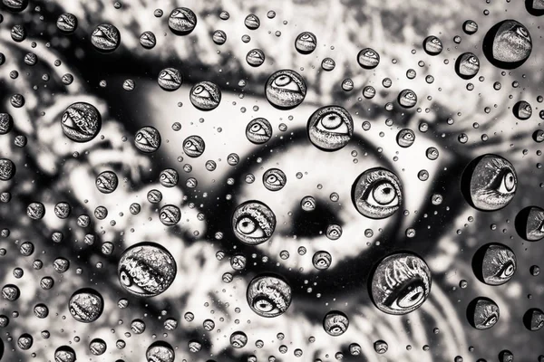 Ojo de cerca a través de gotas de agua en el vidrio — Foto de Stock