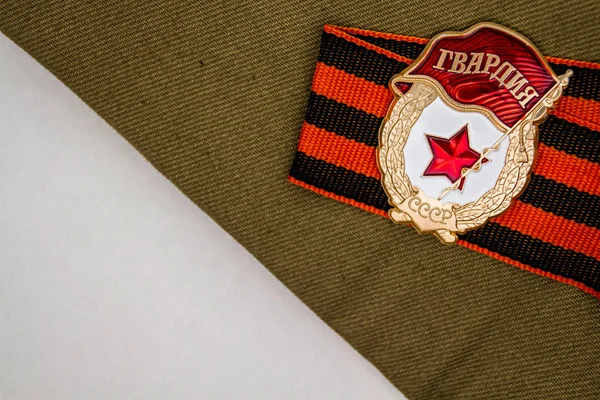Soviet Badge Guard and St. George ribbon, dried flowers and bullet on craft background. Symbolized a Victory Day in Russia. Toned some vintage. Traditional symbols of Victory Day 1945 9 May.
