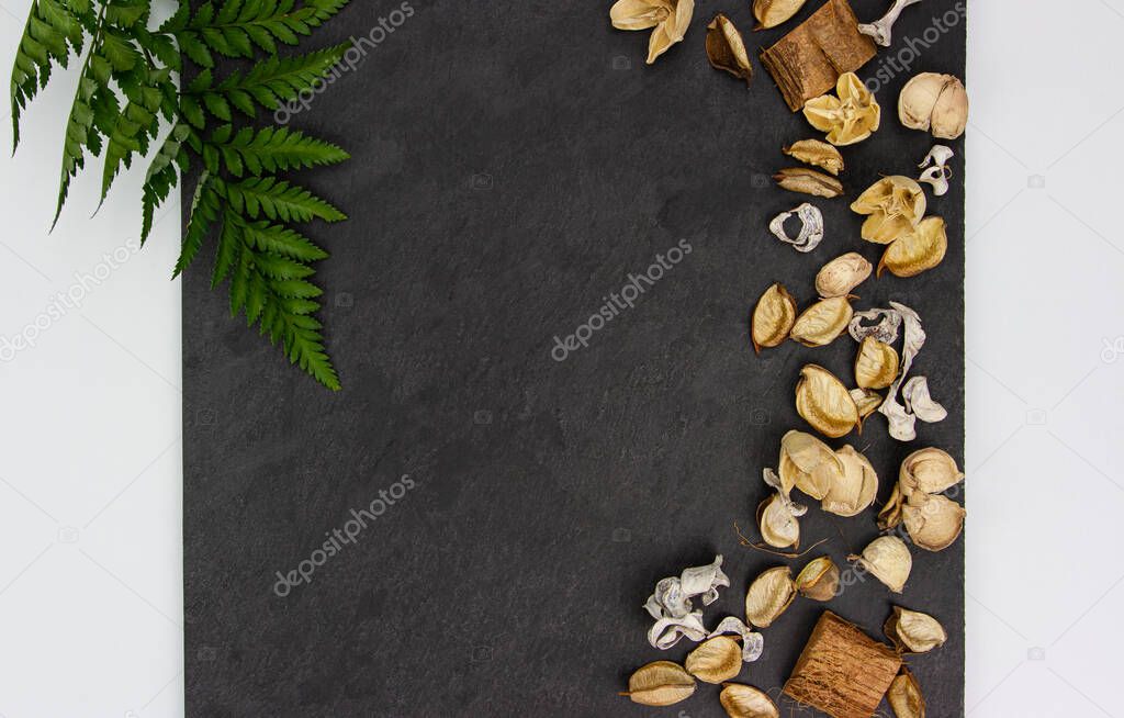 Dried aroma flowers on the dark textured background with green Asplenium leaf. Aromatic Flower fragrance on black background.