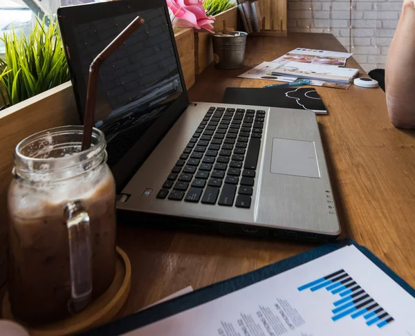 Coffee Cup op een tafel met laptob en grafiek Finance diagram in Stockafbeelding