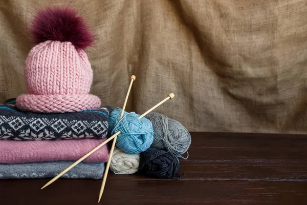 Tejer suéteres de punto caseros y coloridos cerca del sombrero rosa y las bolas de hilo. Prendas de punto hechas a mano — Foto de Stock