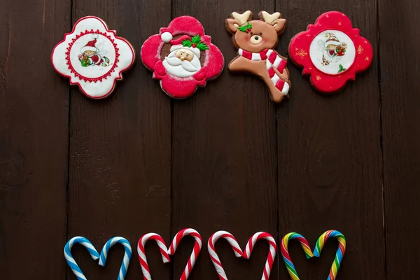 Christmas sweets, gingerbreads and christmas candy cane on wooden background with copyspace for your text