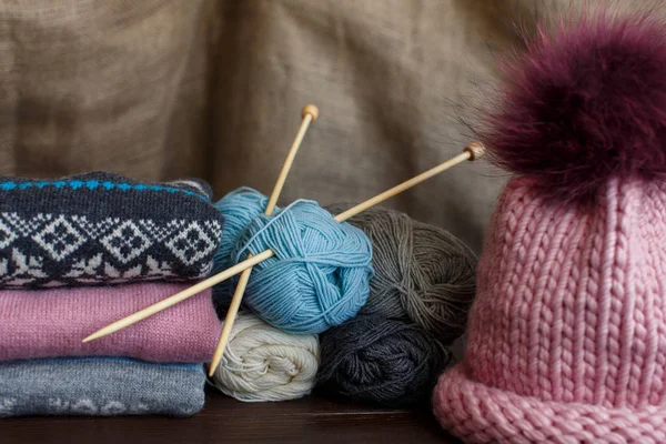 Tejer suéteres de punto caseros y coloridos cerca del sombrero rosa y las bolas de hilo. Prendas de punto hechas a mano — Foto de Stock