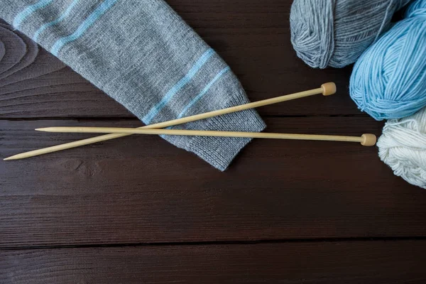 Sticka tillbehör: ärm grå med mint ränder stickad tröja, bollar av garn och nålar för stickning på trä bakgrund med kopia utrymme — Stockfoto