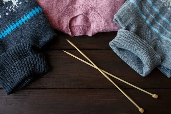 Suéteres y agujas de punto para tejer sobre fondo de madera marrón. Concepto de invierno — Foto de Stock