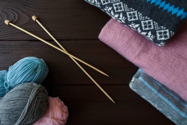 Suéteres y agujas de punto para tejer sobre fondo de madera marrón. Concepto de invierno — Foto de Stock