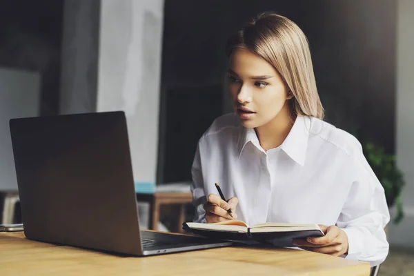 Student studying remotely at home. Young lady sitting in front of laptop, watching at screen and smiling. Isolated