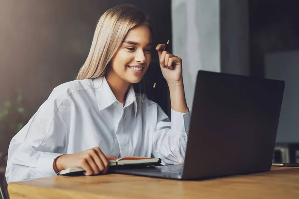 Studenten die op afstand thuis studeren. Jongedame zit achter de laptop, kijkend naar het scherm en glimlachend. geïsoleerd — Stockfoto