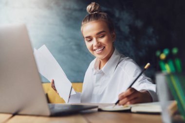 Öğrenci seminere hazırlanıyor, not defterine notlar yazıyor, internetten bilgi arıyor. Kadın çalışıyor.
