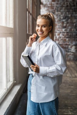 Elinde akıllı telefon ve defter tutan güzel sarışın kız. İş kadını iş için cep telefonu kullanıyor.