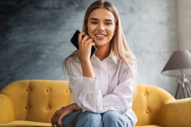 Kadın evde dinleniyor, akıllı telefonu mesajlarda kullanıyor, fotoğrafları paylaşıyor, arkadaşlarla iletişim kuruyor, e-postaları kontrol ediyor