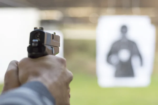 Man Firing Pistol at Target in Shooting Range