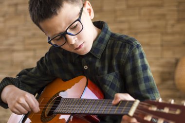 Oturma odasında akustik gitar çalmak gözlüklü çocuk