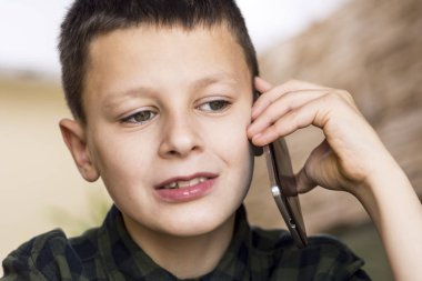Genç çocuk evde cep telefonuyla konuşuyor. Cep telefonu konuşma kavramı.