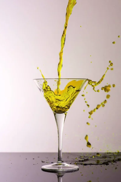 Yellow Cocktail Splashing From Martini Glass Isolated on White Background. Bar Commercials Concept.