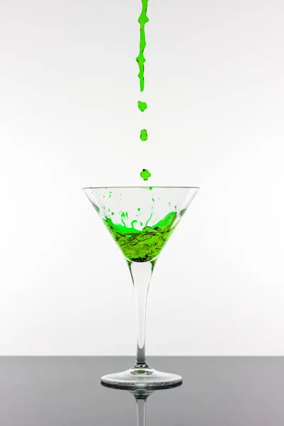 Zelený koktejl stříkající z Martini skla izolovaných na bílém pozadí. Barová reklamy koncepce. — Stock fotografie