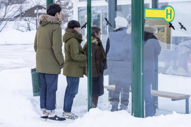 Obertraun, Avusturya - 10 Ocak 2017: Grup insanlar bekleyen otobüs durağında ve takvim soğuk karlı kış günü arıyorsunuz
