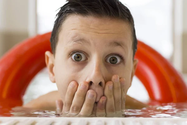 Boy with Funny Face Expression Wears Red Life Ring and Have Fun in the Swimming Pool