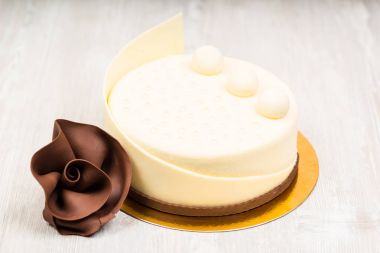 Beyaz çikolatalı kek ve masanın üzerine gül