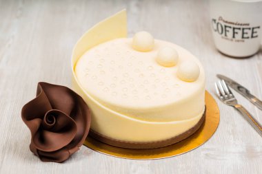 Beyaz çikolatalı kek ve kahve ile gül masada