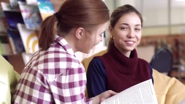 S úsměvem mladých studentek v knihovně mluvit k sobě navzájem