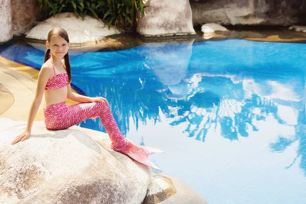 Mermaid girl with pink tail on rock at poolside — Stock Photo, Image