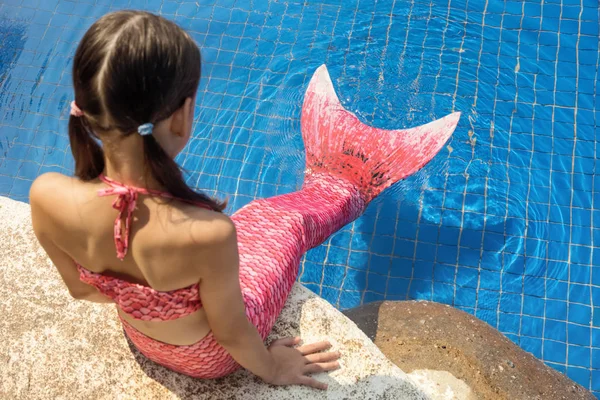 Mermaid girl with pink tail on rock at poolside put feet in wate — Stock Photo, Image