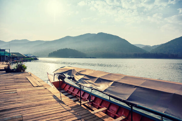 Boat in sun light at pier on mountain lake