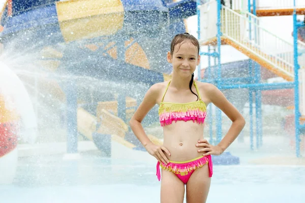 Lächelndes Mädchen, das unter Wassertropfen steht. verschwommene Wasseroberfläche — Stockfoto