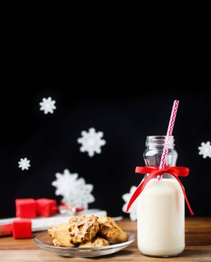 Vintage şişe süt kırmızı kurdele ve siyah arka plan üzerinde ahşap masa çerezleri Noel babalar