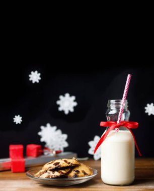 Vintage şişe süt kırmızı kurdele ve siyah arka plan üzerinde ahşap masa çerezleri Noel babalar