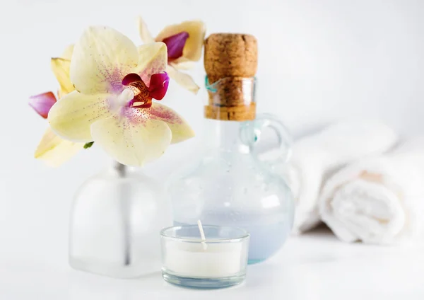 Aceite de aroma, orquídea y vela sobre mesa blanca. Estilo de vida saludable, spa —  Fotos de Stock