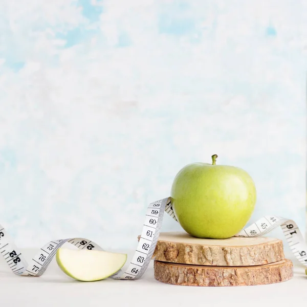 Grönt äpple med måttband på träbord. Hälsosam livsstil, vegetarianmat, detox — Stockfoto