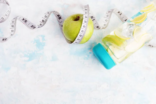Bovenaanzicht plat lag fles detox water met groene appel en meetlint — Stockfoto