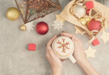 Üstten Görünüm düz lay beyaz fincan cappuccino ile toz tarçın kar tanesi Noel oyuncaklar arasında tutan eller